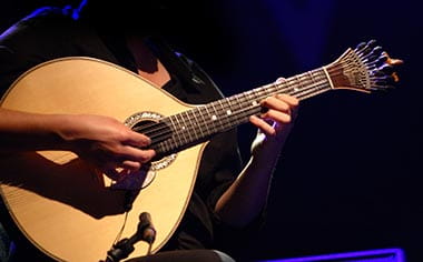 A musician playing fado music on a traditional Portuguese guitar